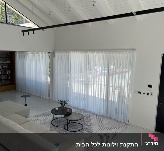 וילונות לבנים שקופים תלויים על חלונות גדולים